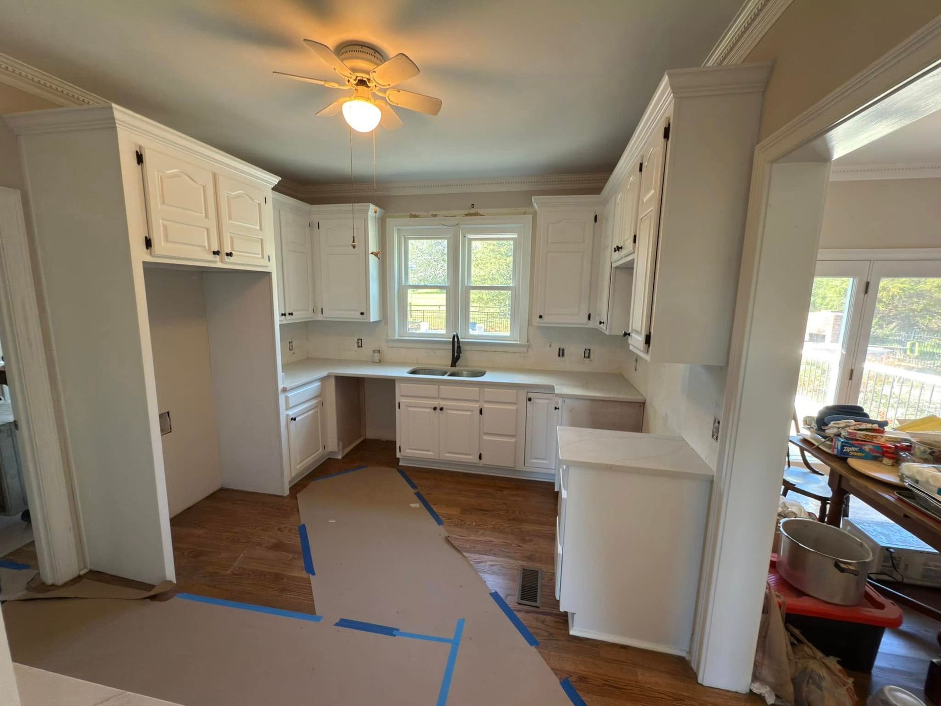 A kitchen with white cabinets and a ceiling fan.