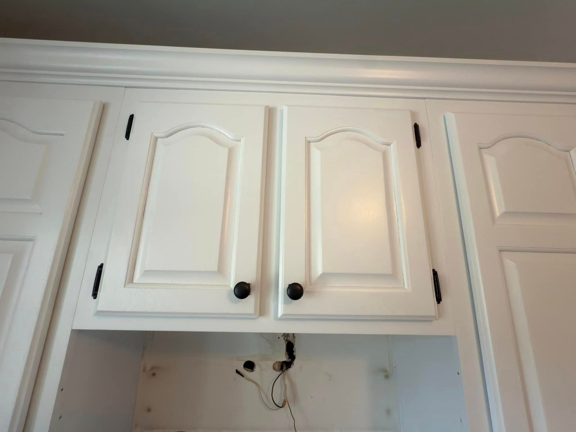 A kitchen with white cabinets and black knobs