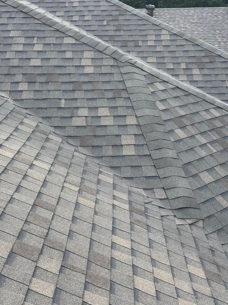 A high-angle view of a grey architectural shingle roof with intersecting pitches and ridges.