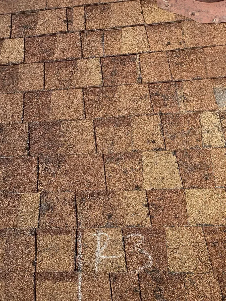 A paved surface of textured, brown square tiles with a white, handwritten 