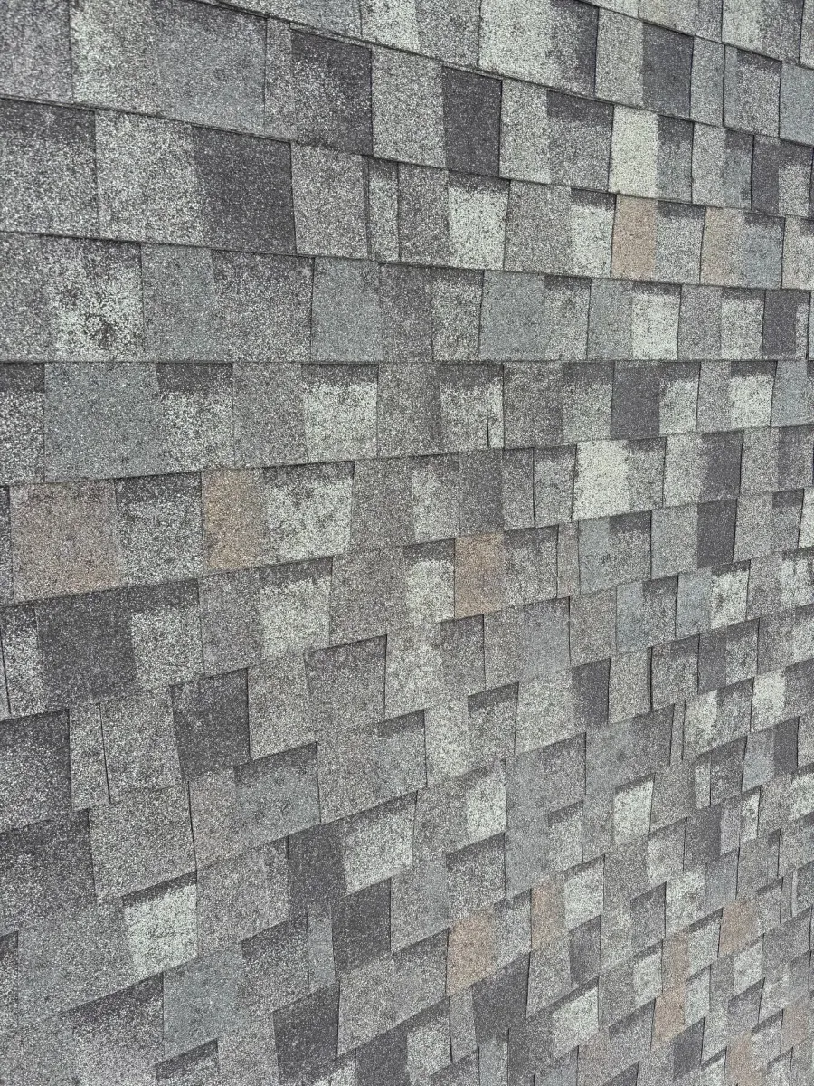 A wall texture consisting of rectangular stone tiles in varying shades of grey, black, and light beige.