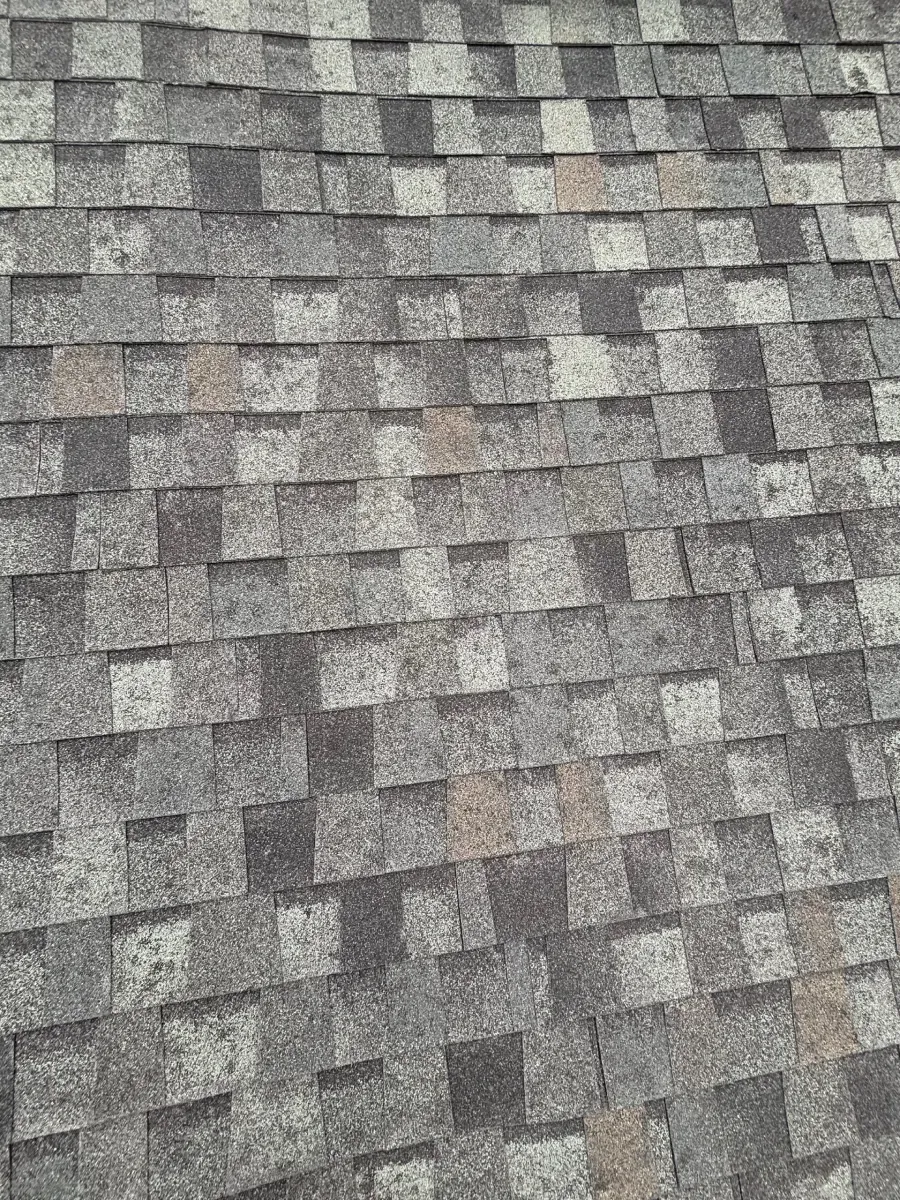 Close-up view of overlapping grey and charcoal asphalt architectural roof shingles with subtle tan highlights.