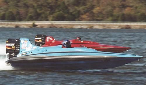 Two racing boats, one blue and one red, speeding across water.