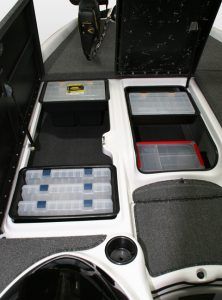 Open compartments in a boat with various tackle boxes and cup holder.