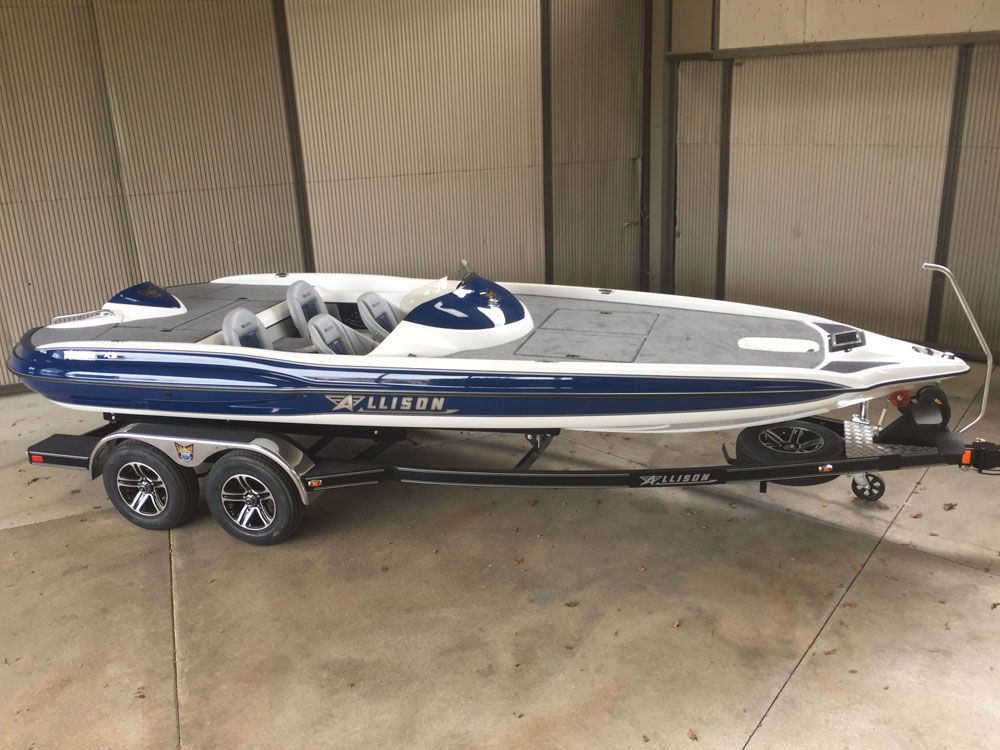 Blue and white Allison boat on a trailer, parked inside a warehouse.