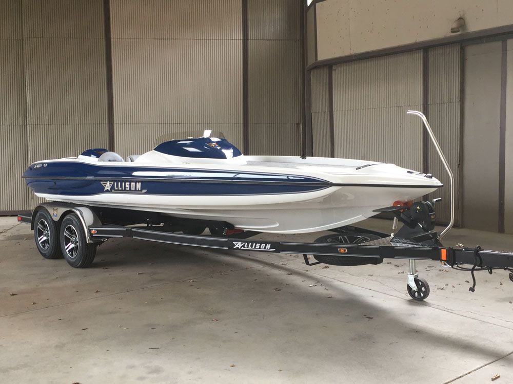 Blue and white boat on a trailer, inside a warehouse.