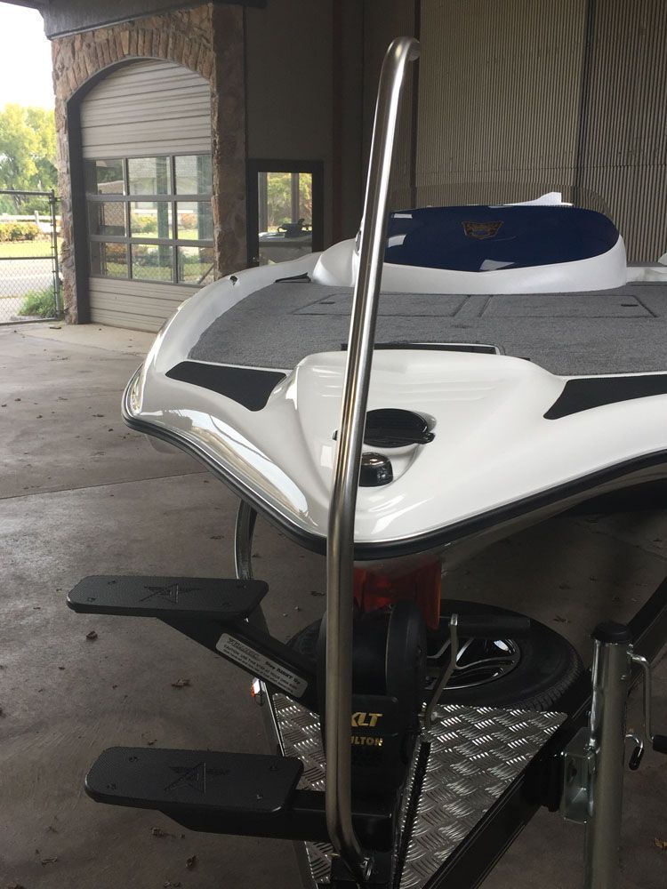 Boat on a trailer with a stainless steel handrail, black steps, and a white boat hull.