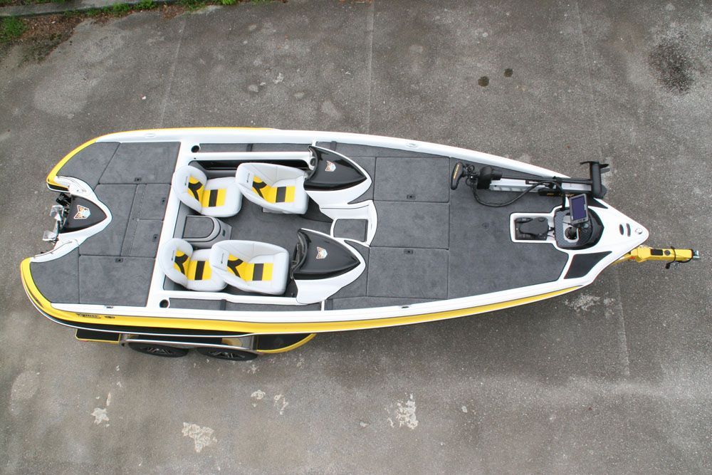 Overhead view of a yellow and white bass boat on a trailer, with gray flooring and yellow seats.