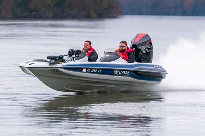 Two men in a speed boat on water. The boat is gray and blue with a large black motor.
