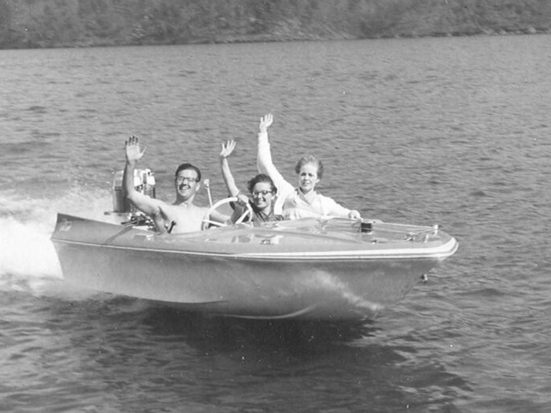 People in a bass boat  wave on a lake, water splashing.