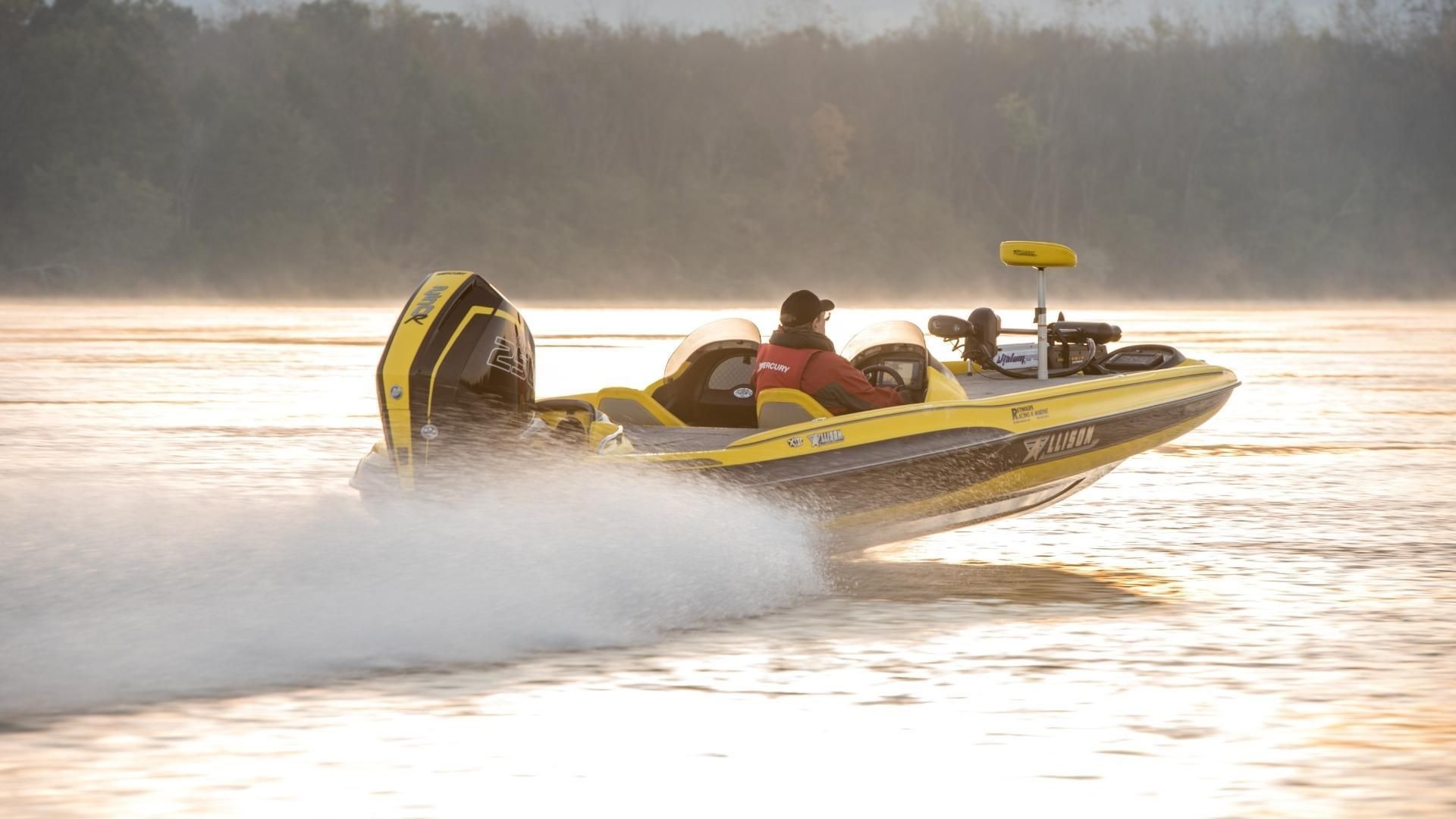 Yellow and black bass boat speeding on a foggy lake, person at the helm.