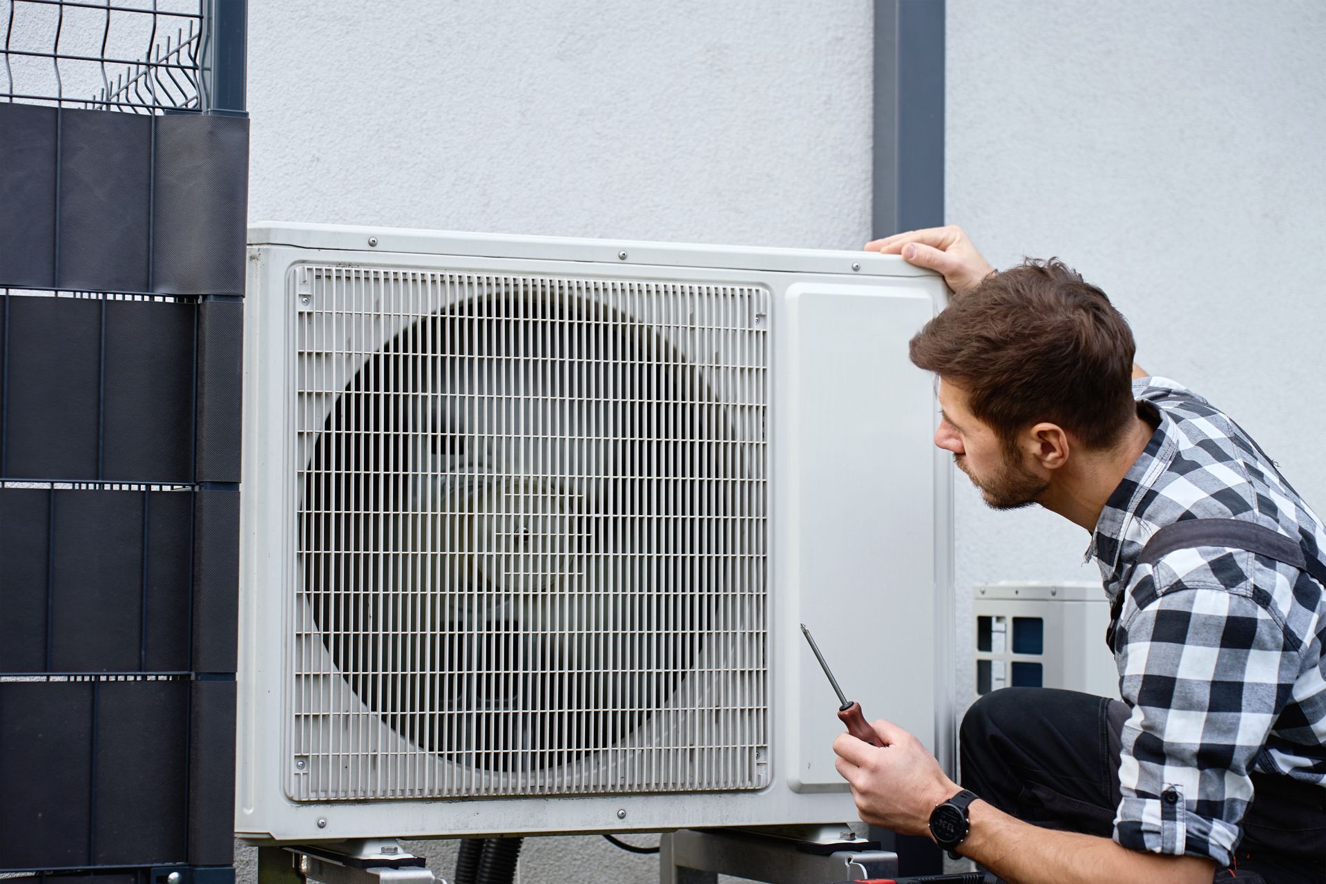 HVAC tech checking outdoor AC unit for maintenance and performance.  