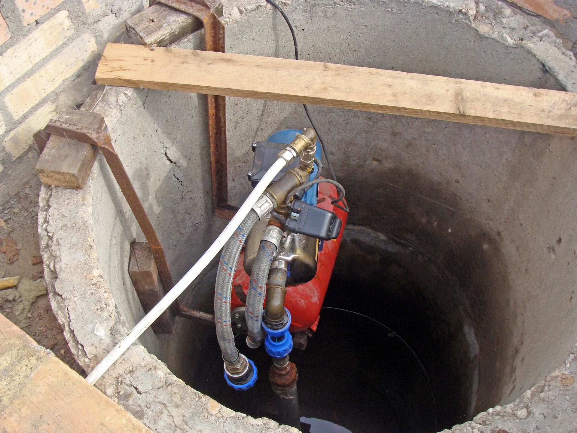Submersible well pump installed in a concrete pit.