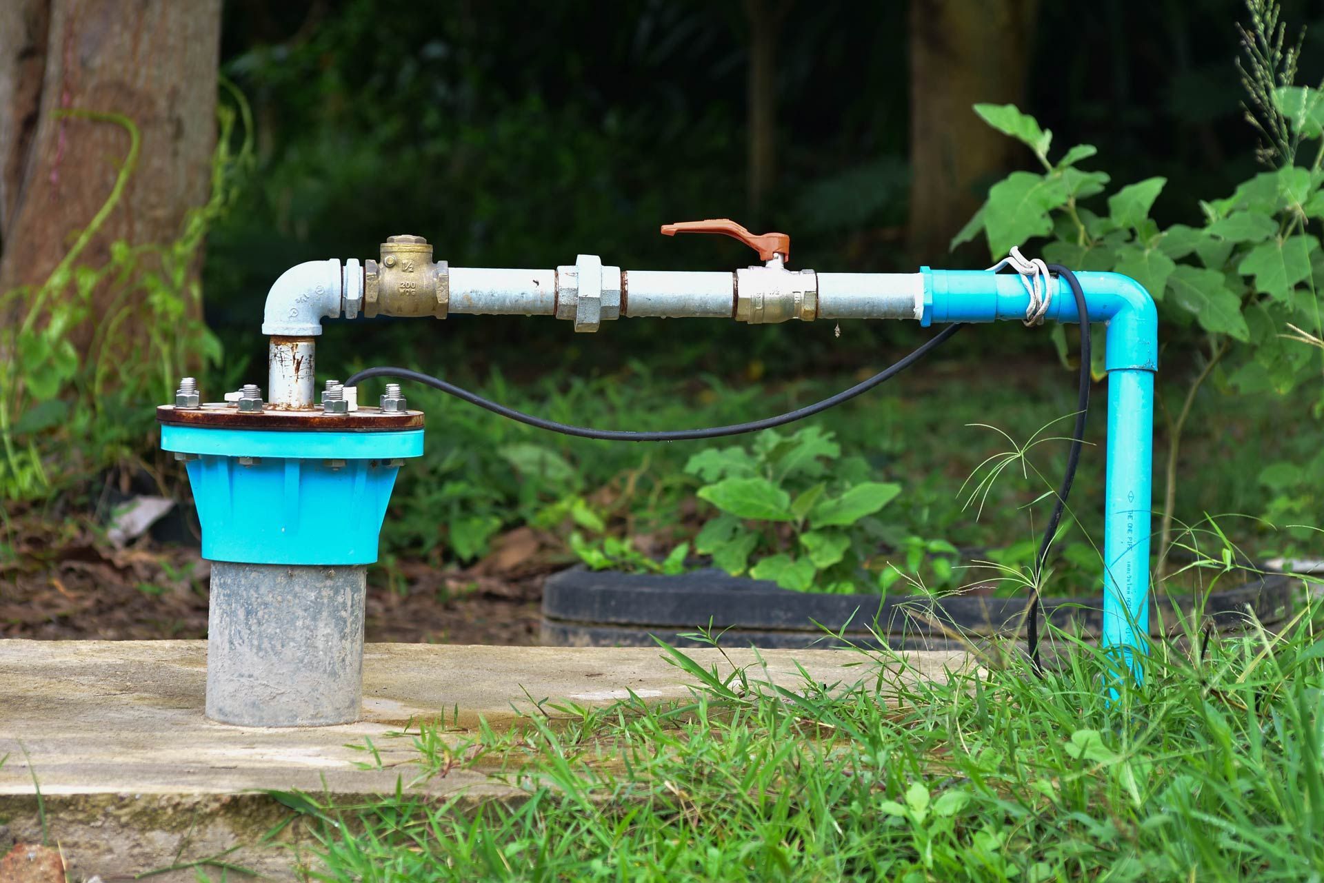 Outdoor well pump with connected PVC piping.