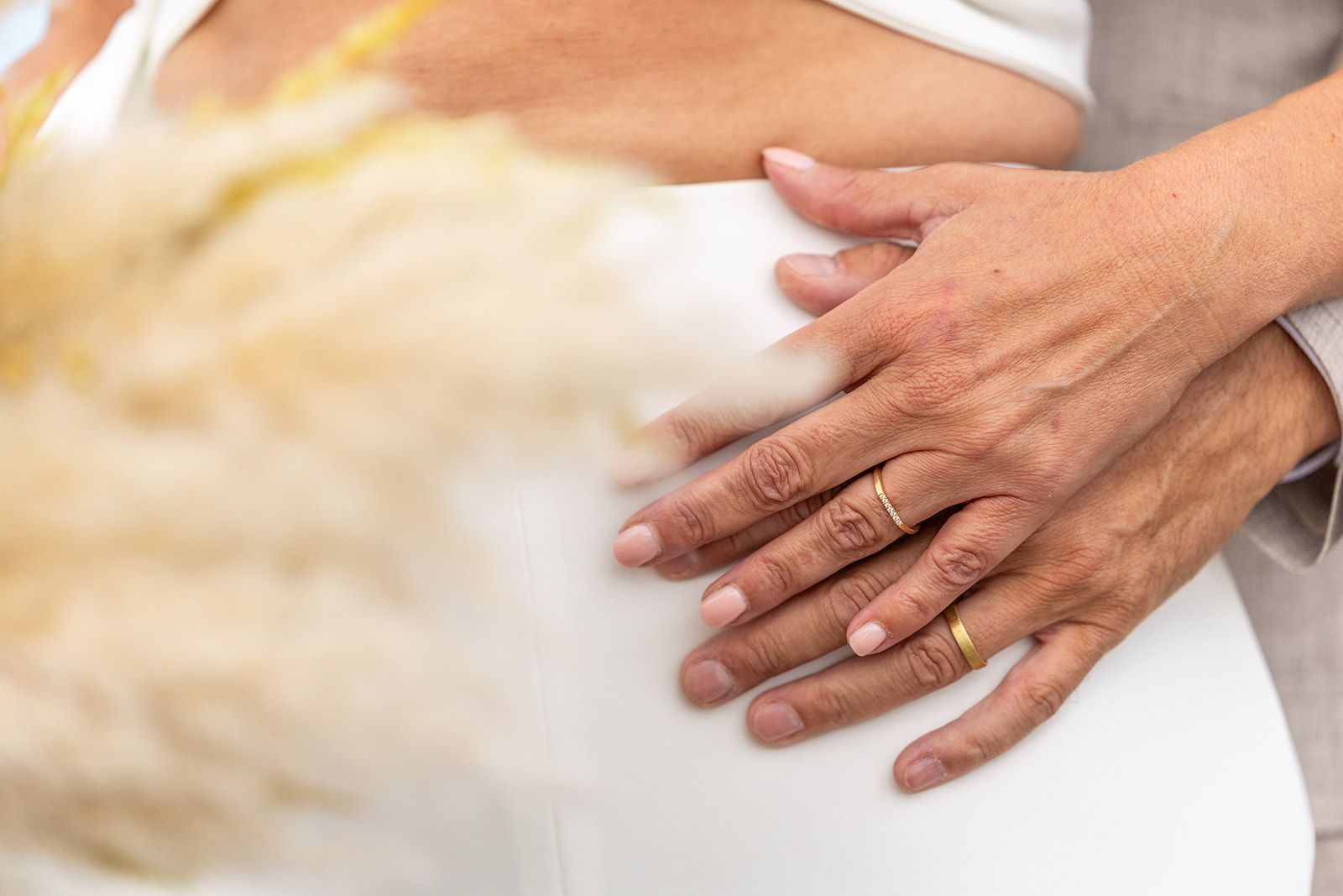 Een bruidspaar raakt elkaars voorhoofd aan en lacht voor een stenen gebouw.