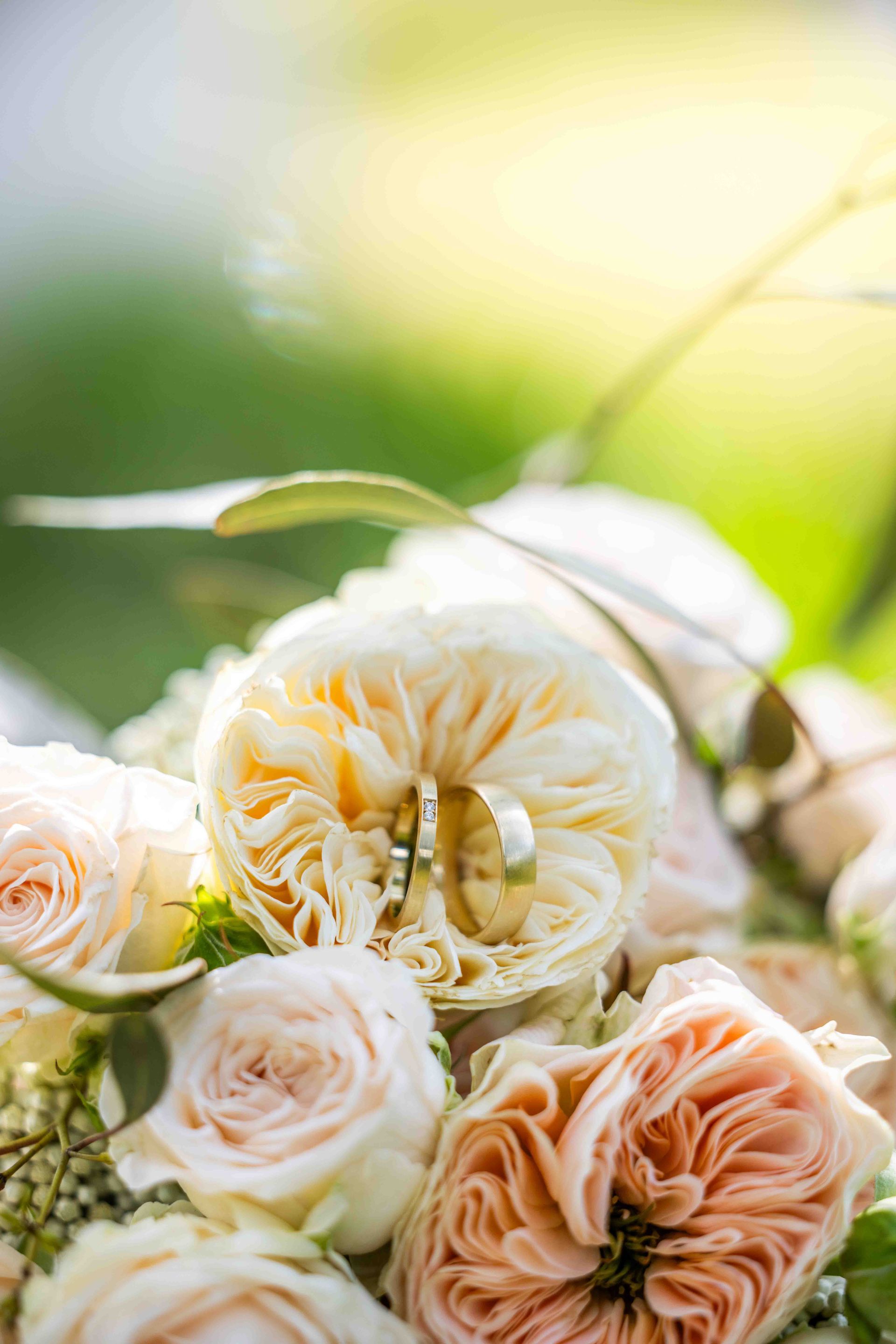 Trouwringen in een boeket van perzik- en crèmekleurige rozen.