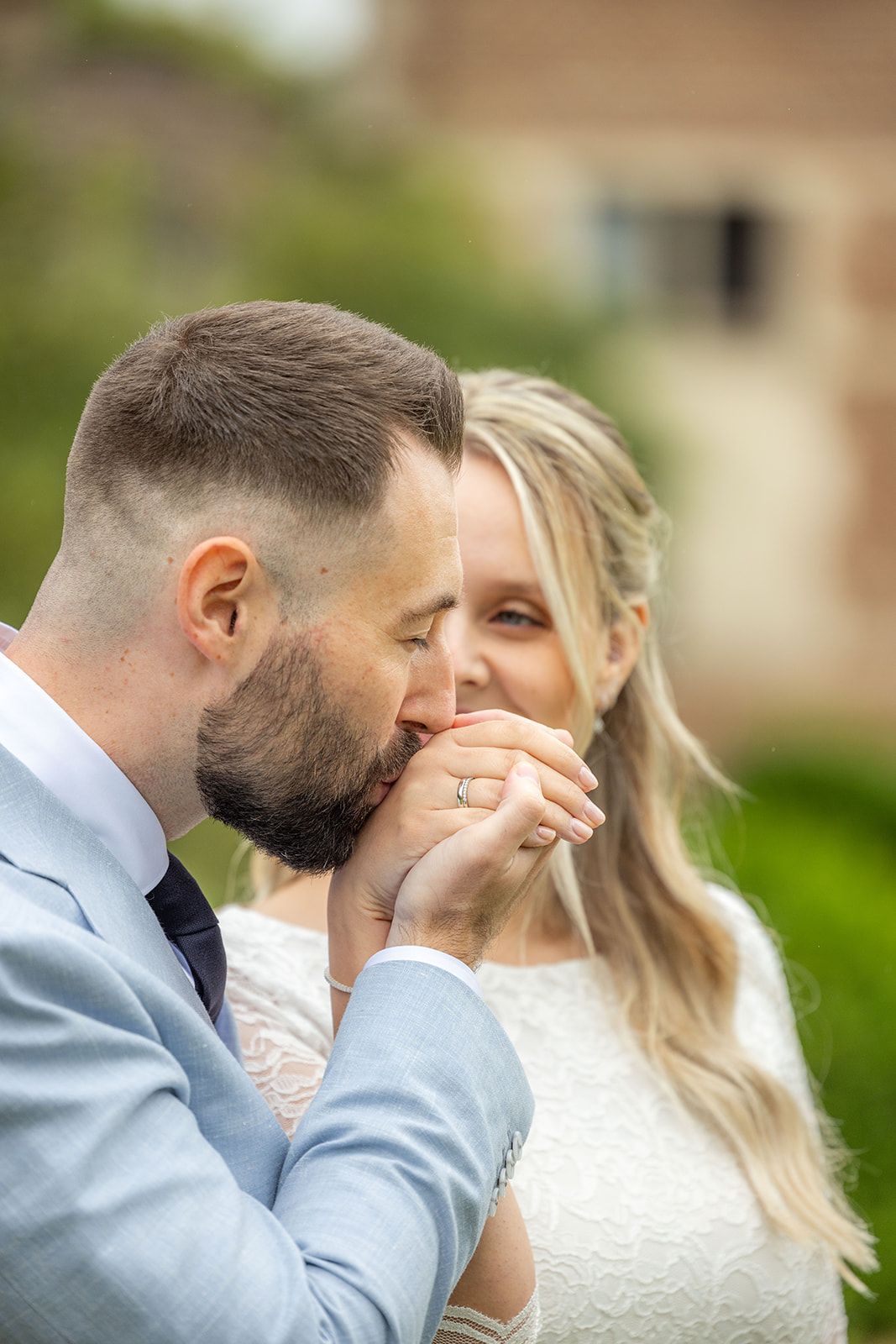 Een stel loopt hand in hand, glimlachend, over een pad; de bruid in een witte jurk, de bruidegom in een roestbruin pak.