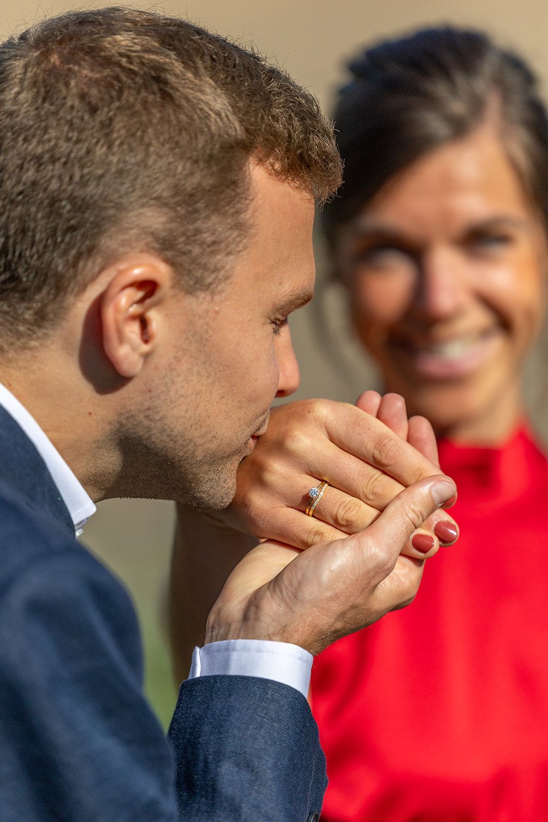 Een bruidspaar raakt elkaars voorhoofd aan en lacht voor een stenen gebouw.