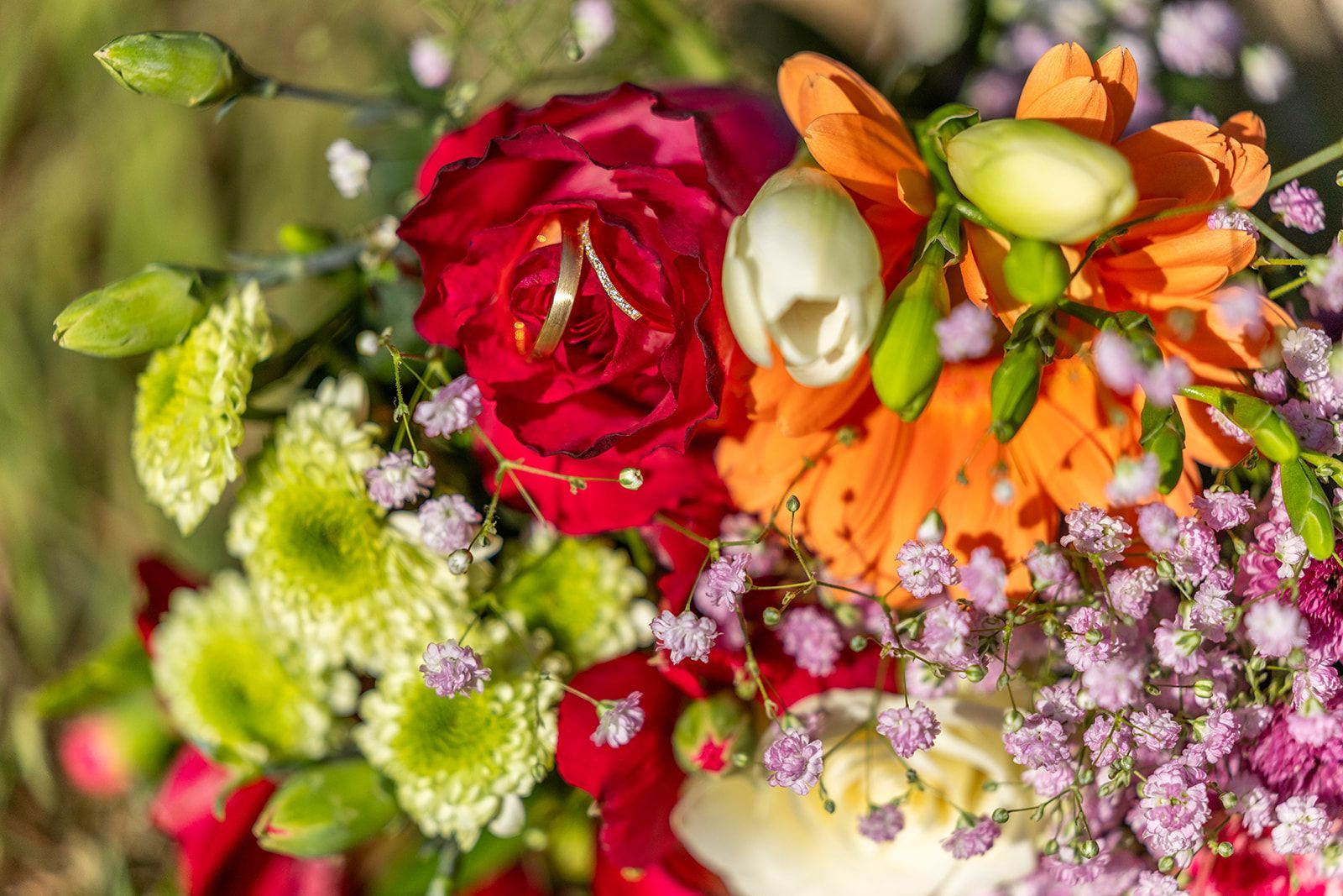 Een stel loopt hand in hand, glimlachend, over een pad; de bruid in een witte jurk, de bruidegom in een roestbruin pak.