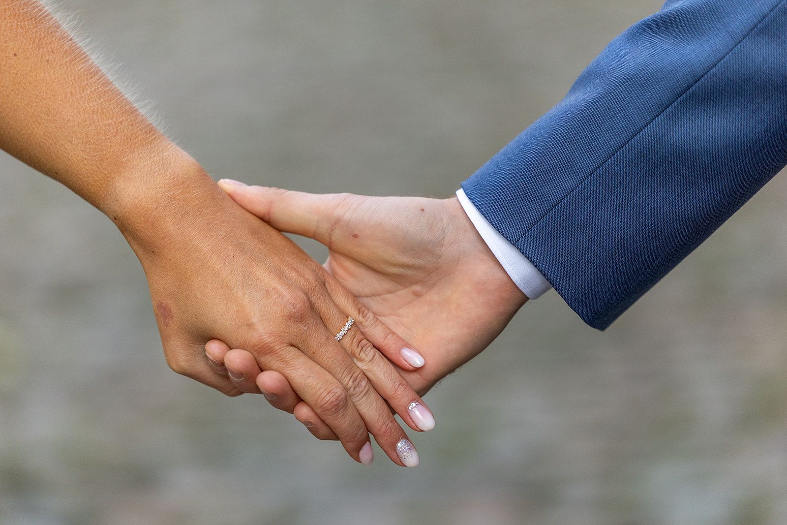 Persoon in blauw jasje houdt hand in hand met persoon die ring draagt.