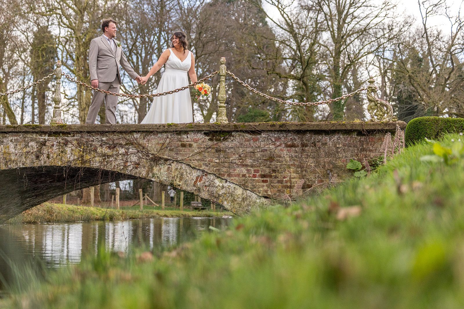 Bruid in kanten topje lacht en houdt de hand van de bruidegom vast. Oceaan op de achtergrond. Zonnige dag.