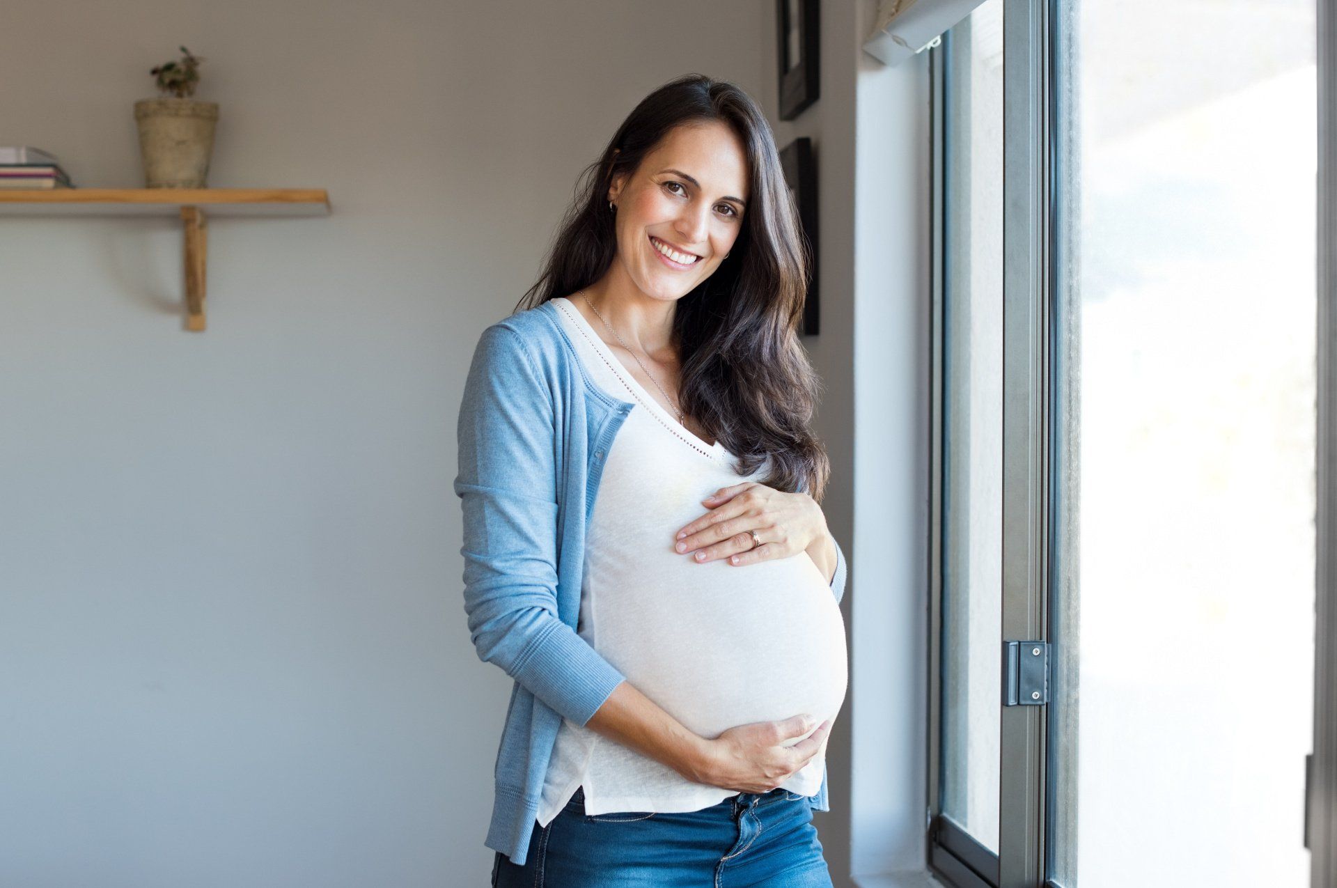 smiling pregnant woman next to window