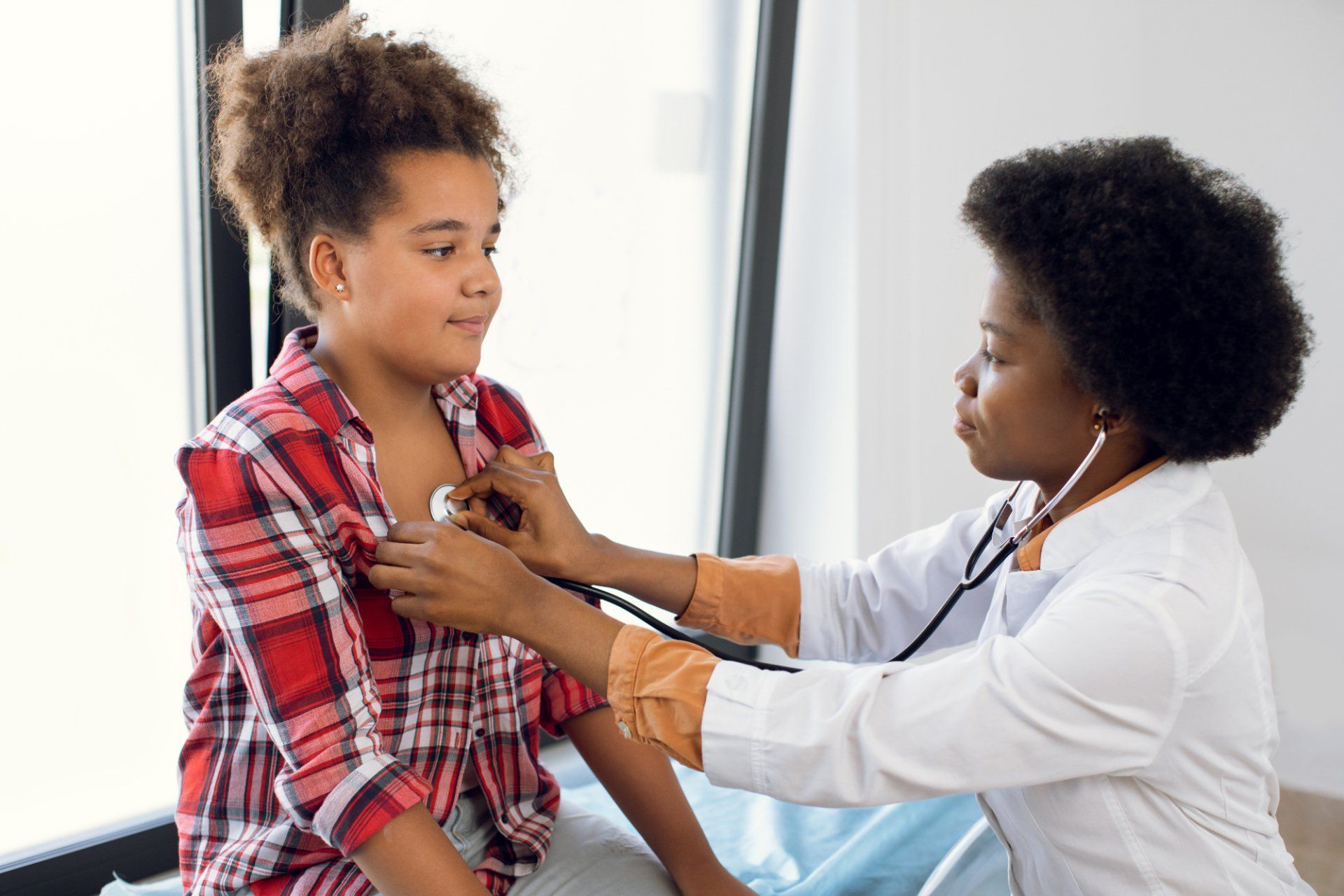 pediatrician high-fiving young female patient with mother
