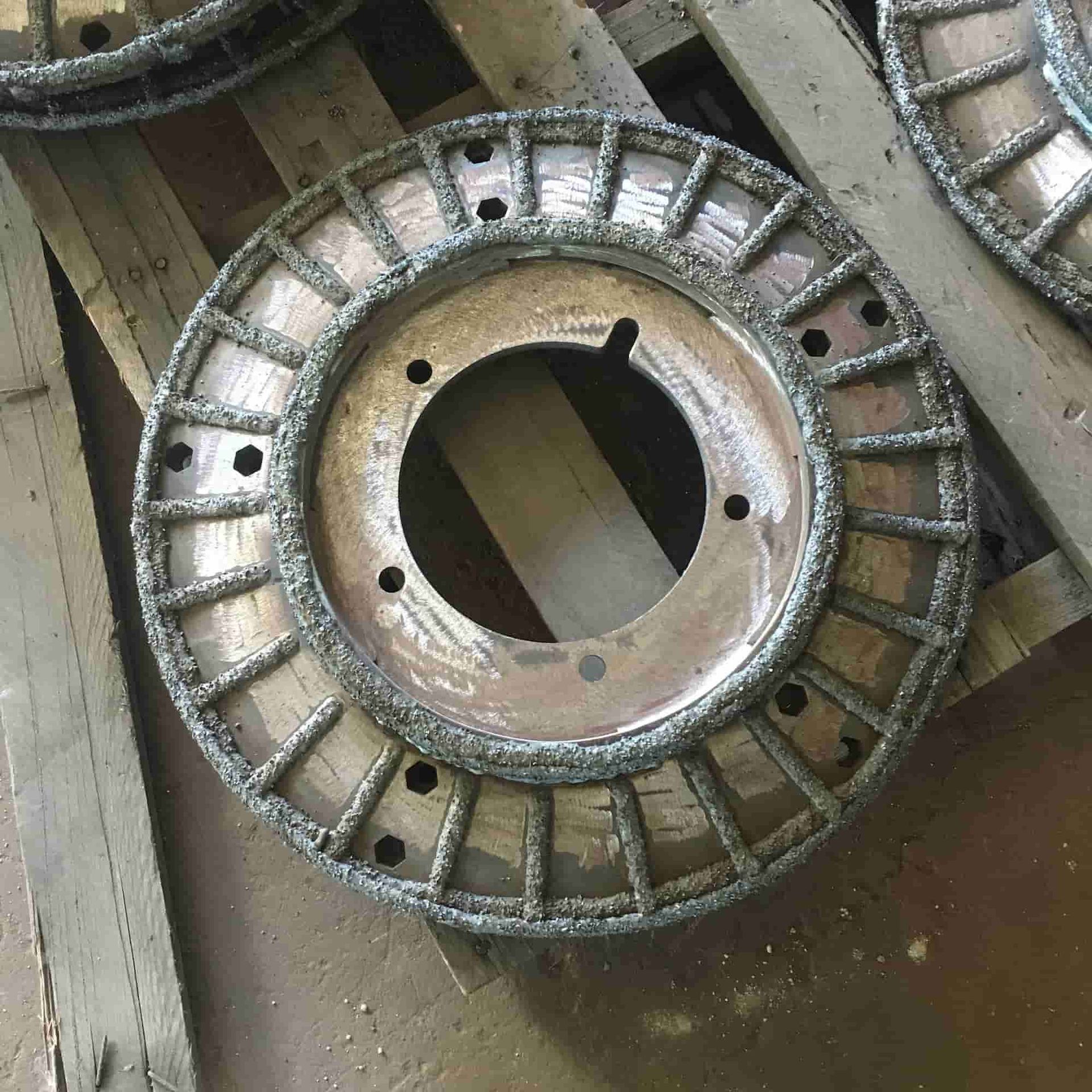 A Wheel With Holes in It is Sitting on a Wooden Pallet — North Queensland Hard Facing (NQHF) In Fredericksfield, QLD