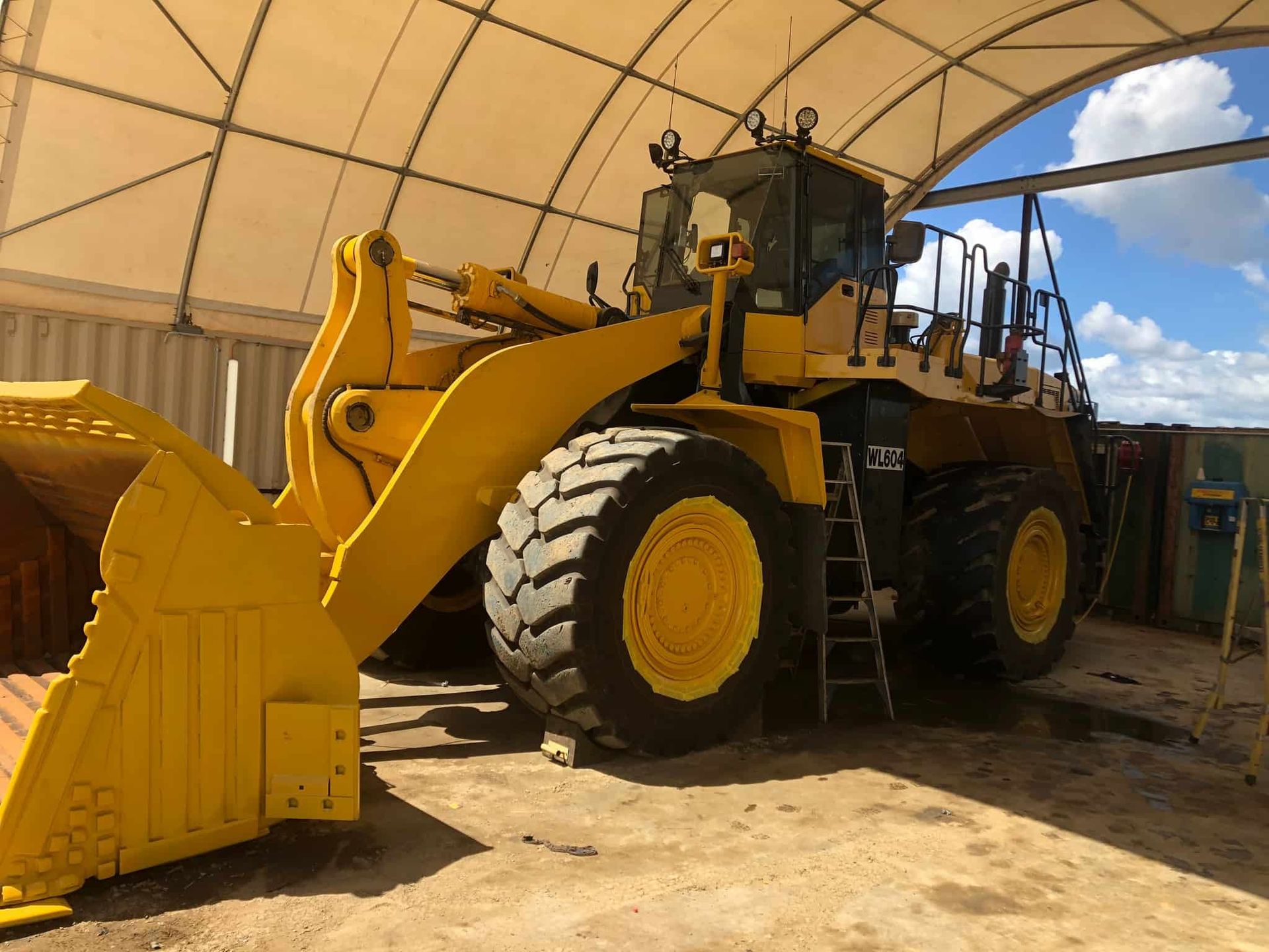 A large yellow bulldozer is parked under a tent — North Queensland Hard Facing (NQHF) In Hunter Valley, NSW
