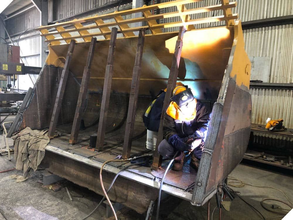 A Man is Welding a Large Piece of Metal in a Factory — North Queensland Hard Facing (NQHF) In Fredericksfield, QLD