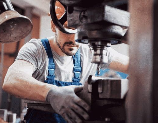 A Man is Working on a Machine in a Factory — North Queensland Hard Facing (NQHF) In Fredericksfield, QLD
