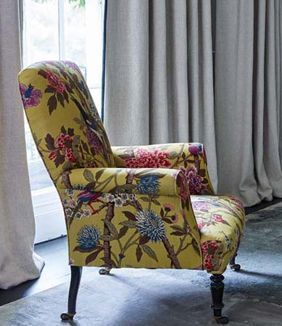 beautiful yellow chair with a floral pattern sitting in front of a window .