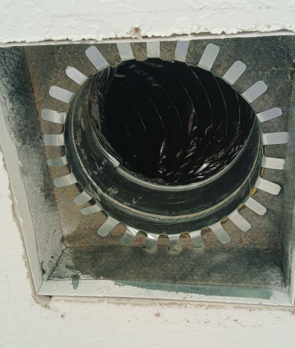 A person’s hands inserting a pleated air filter into a ceiling-mounted HVAC vent.