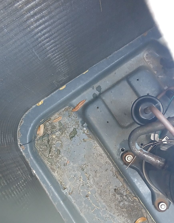 A gloved hand uses a vacuum hose to clean a dusty floor, with light catching the swirling dust particles.