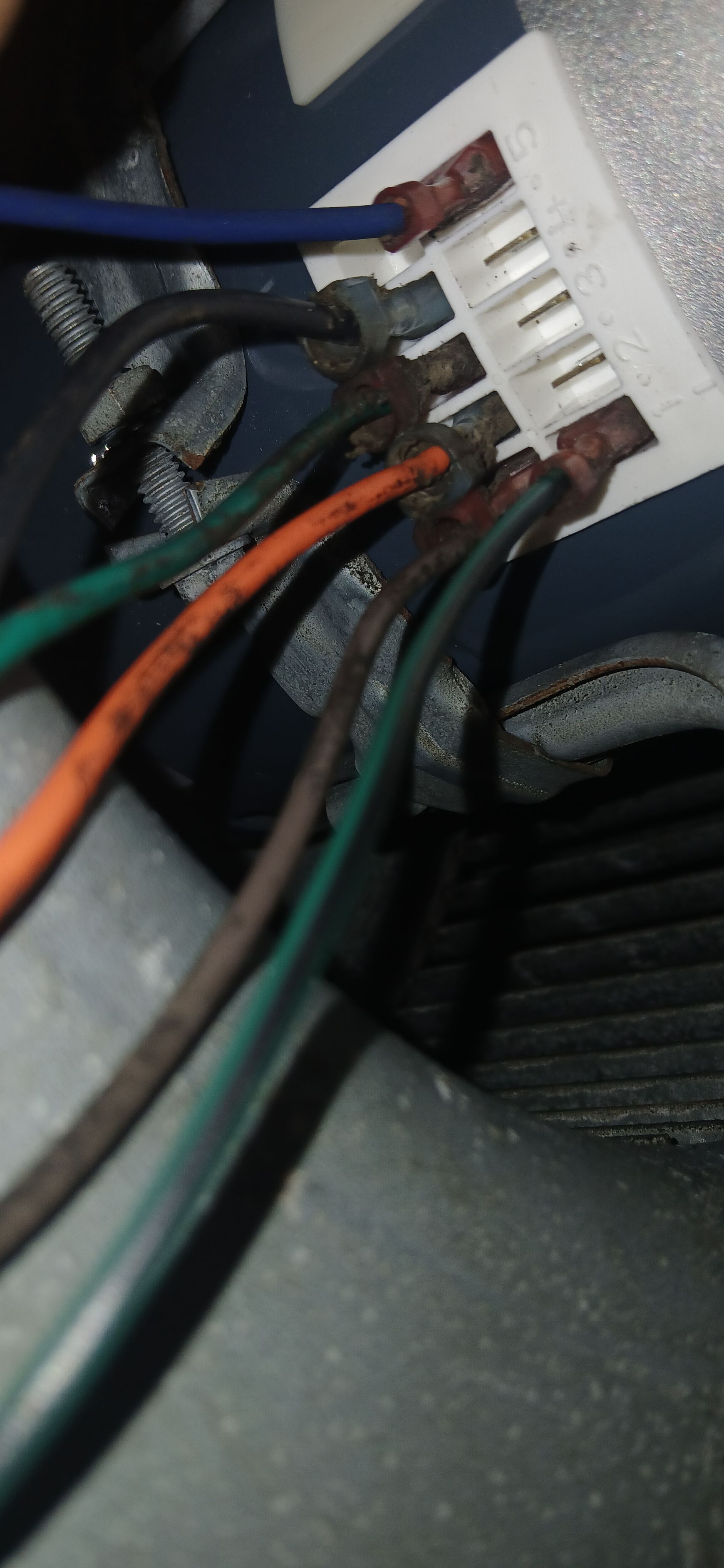 A white electrical terminal block with several colored wires, including blue, black, green, orange, and brown, attached.