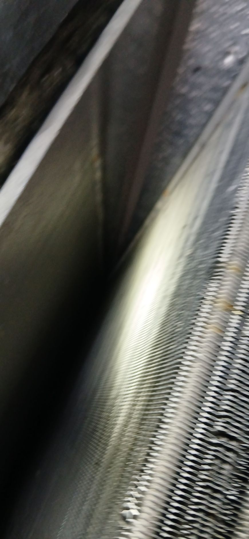 Close-up view of an air conditioning evaporator coil showing a gap between the metallic metal fin assembly and paneling.