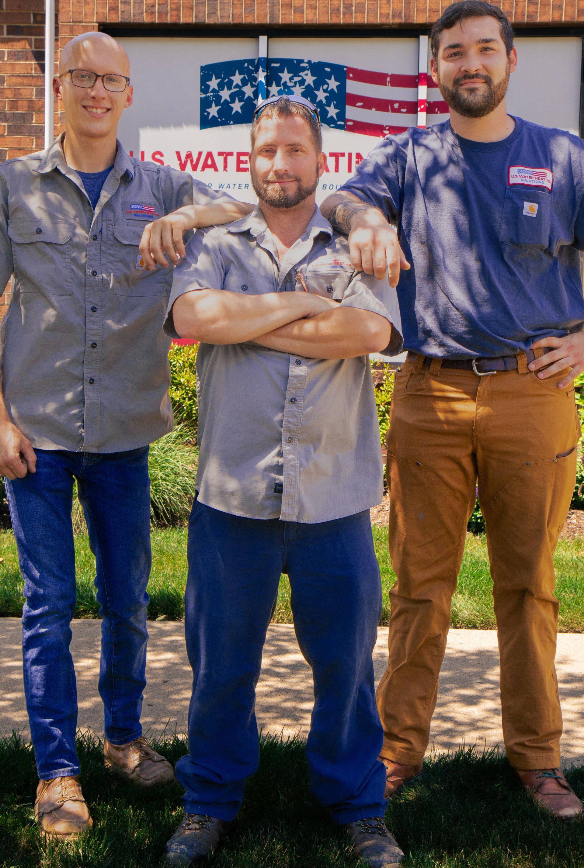 Three water heater service technicians pose in front of U.S. Water Heating Solutions office