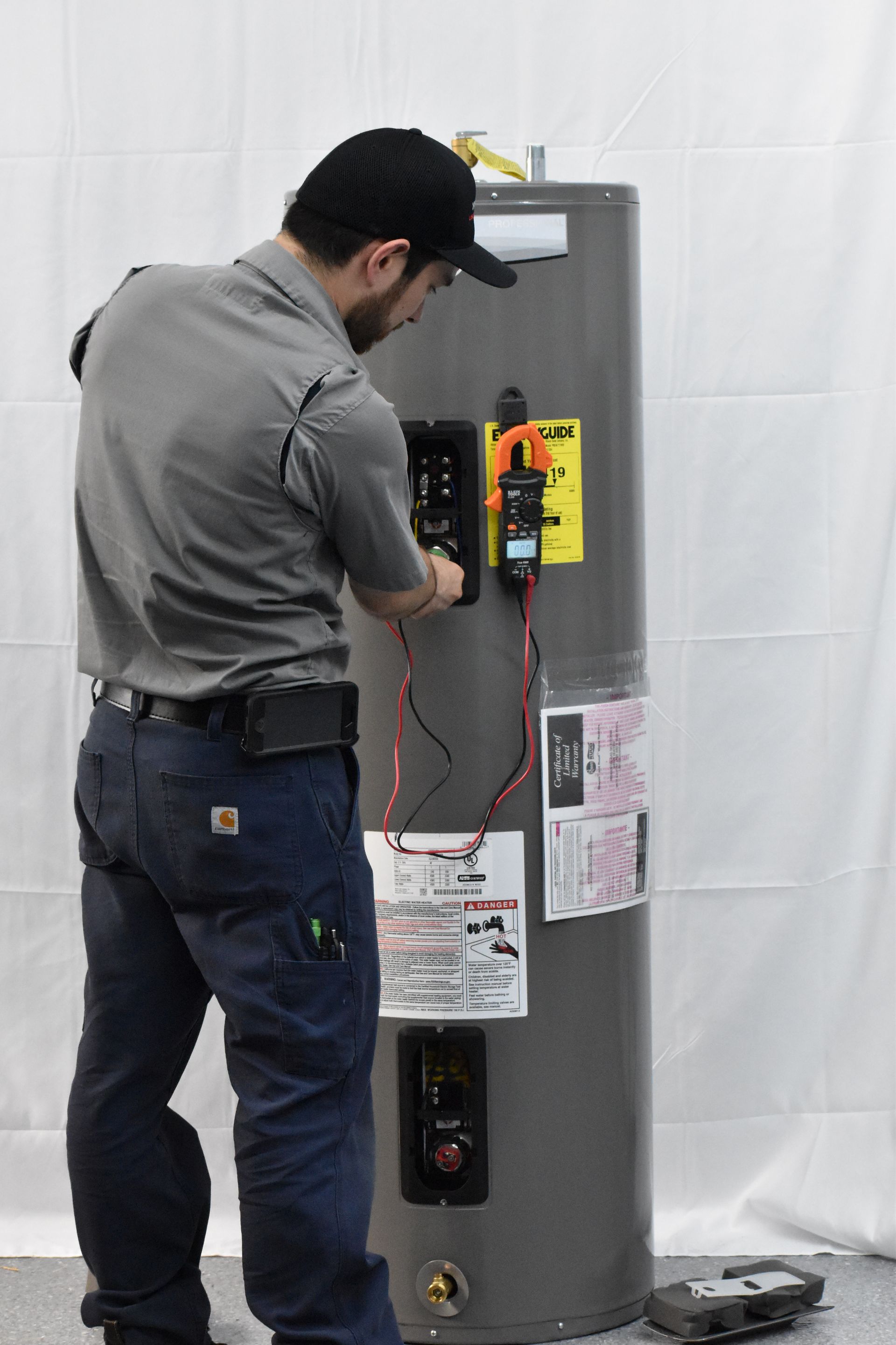 Technician diagnosing and repairing a Rheem residential electric water heater