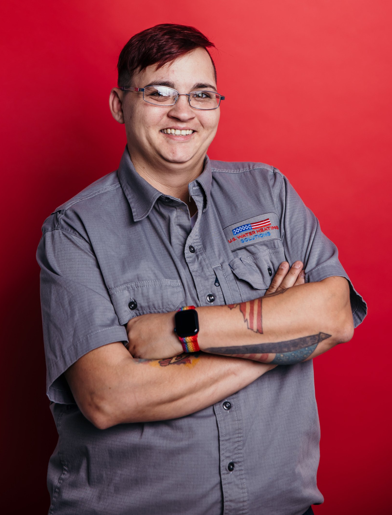Water Heater Repair Technician Stacey Poses for Headshot with red background