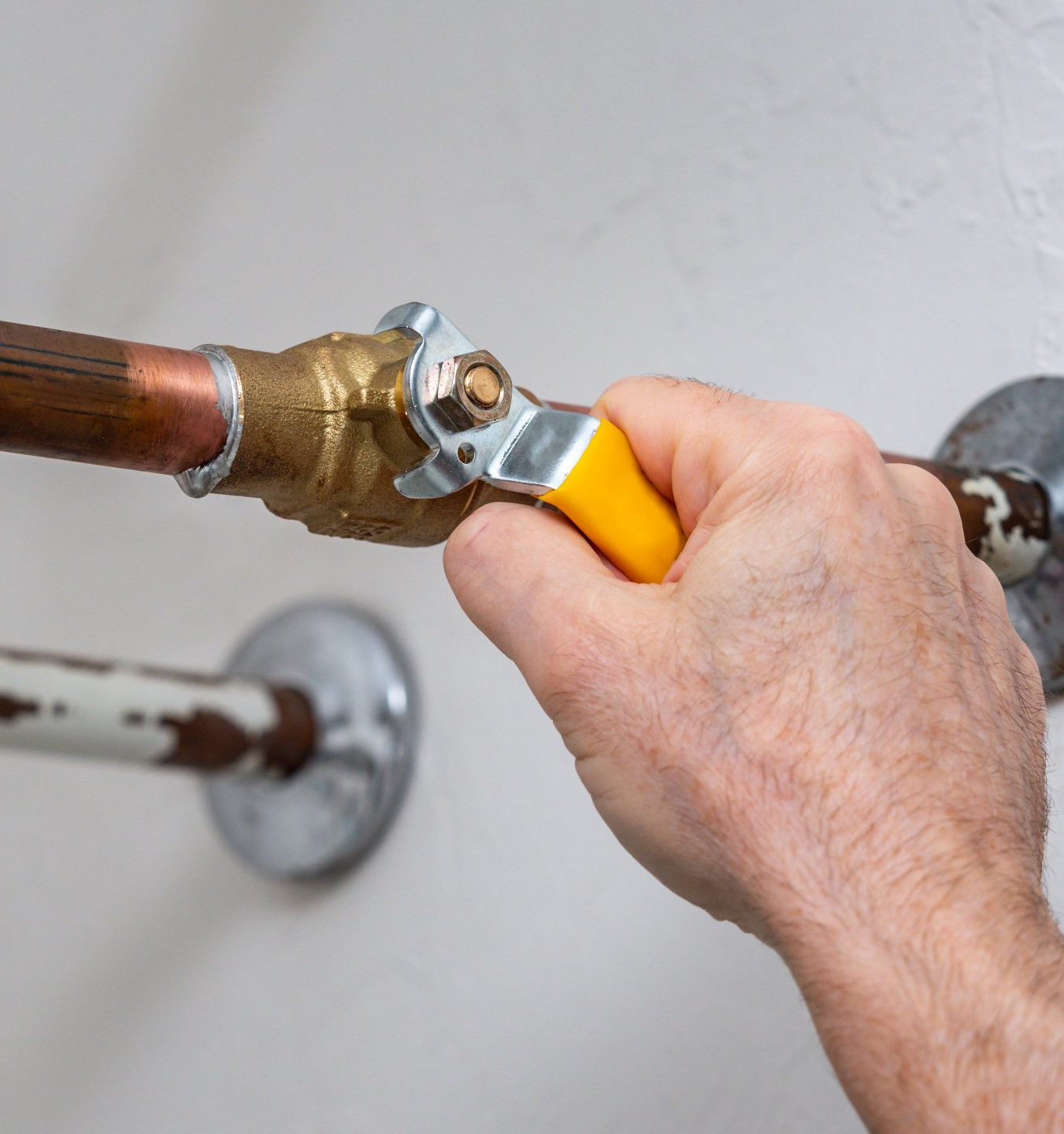 Hand turning off water supply to water heater