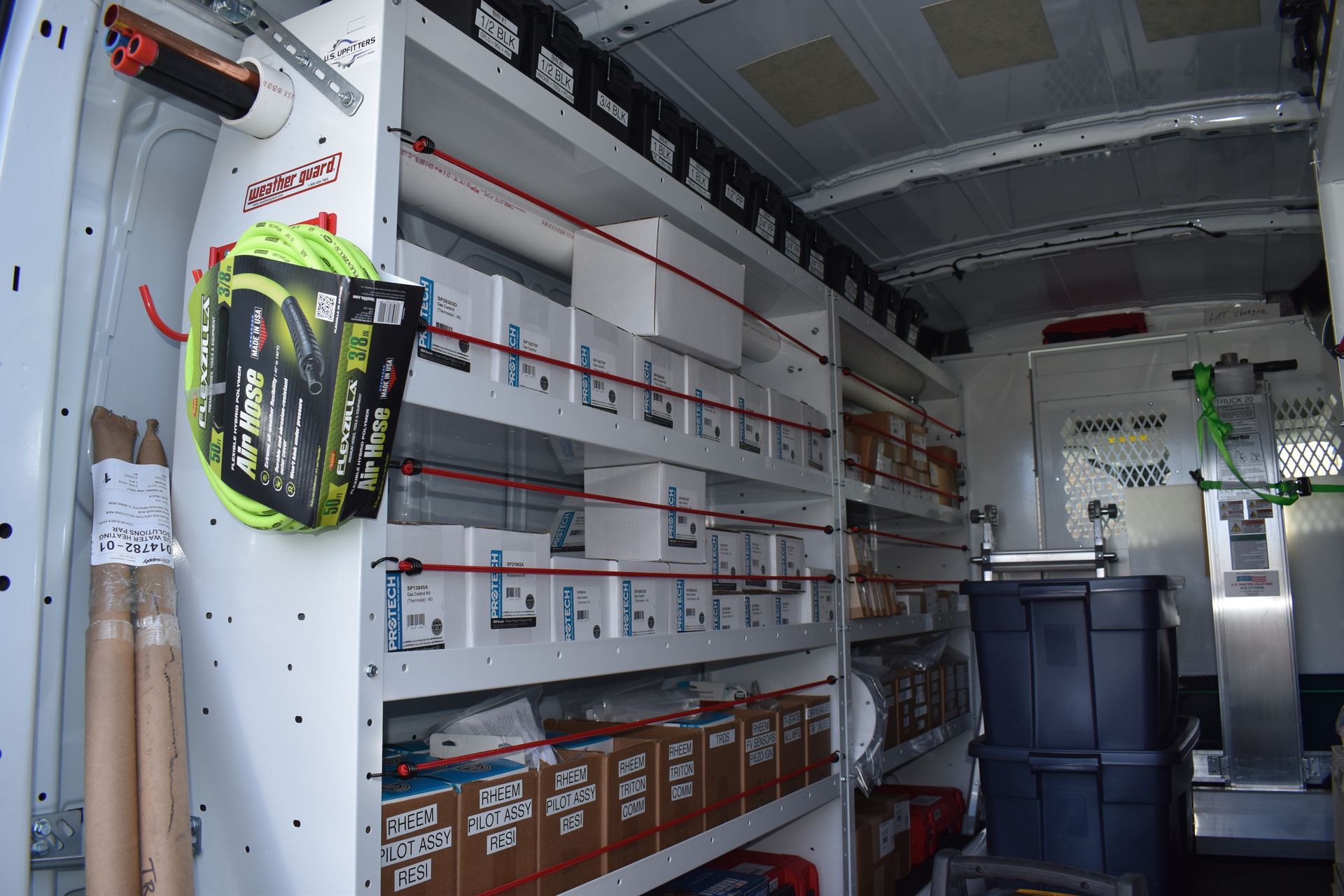 Inside water heater service technician service vehicle, stocked with two shelves of gas valves