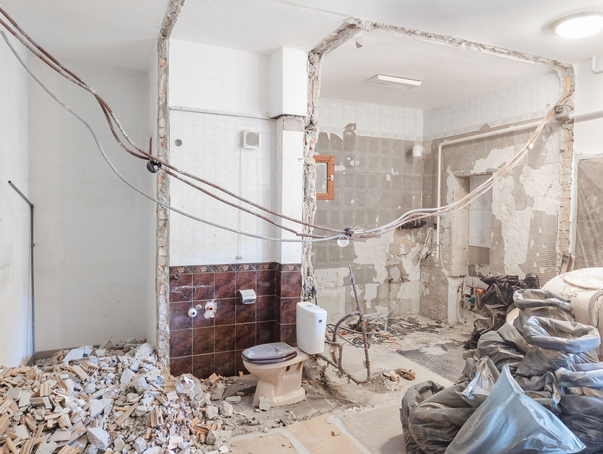 A bathroom under construction with a toilet and a pile of trash.