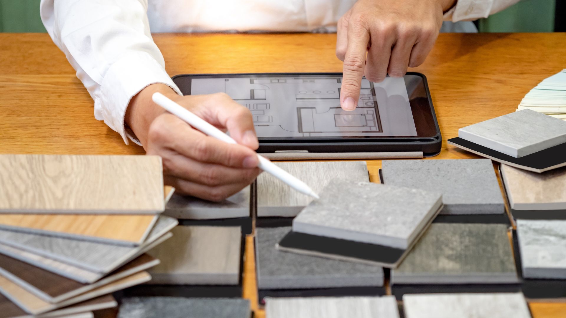 A person is sitting at a table using a tablet and a pen.