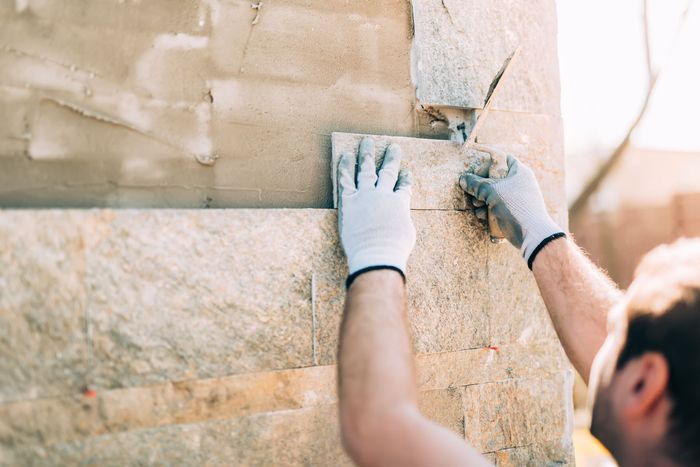 A man wearing white gloves is installing a stone wall.
