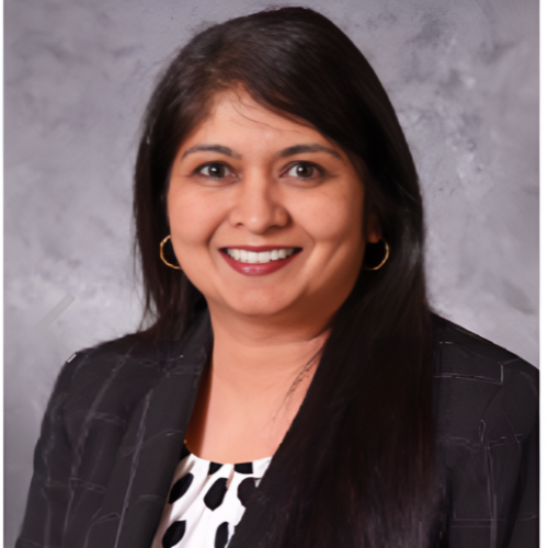Woman in black and white patterned jacket smiles at the camera, wearing gold hoop earrings.