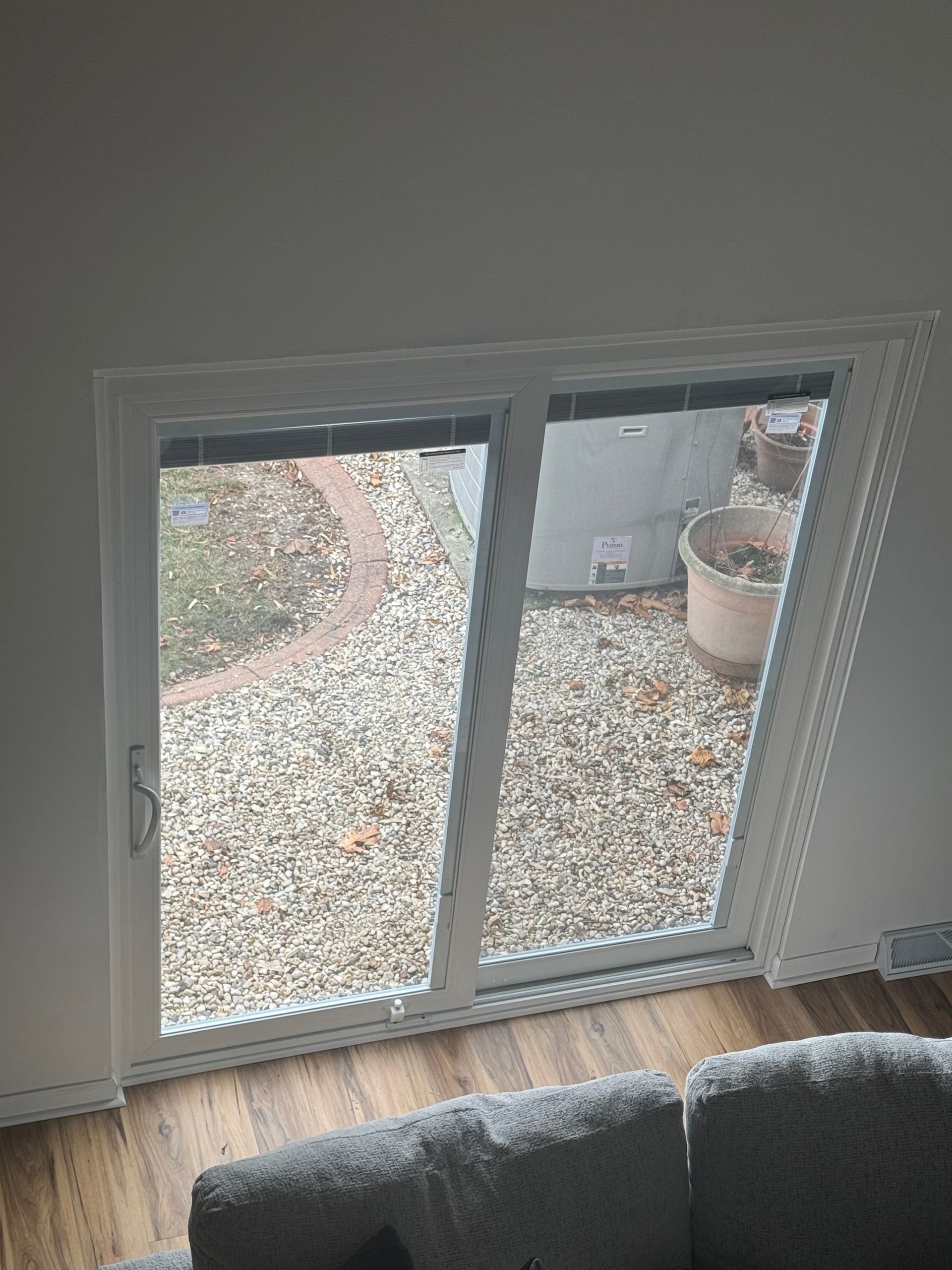 White sliding door, open to a gravel patio with a brick pathway and potted plant.