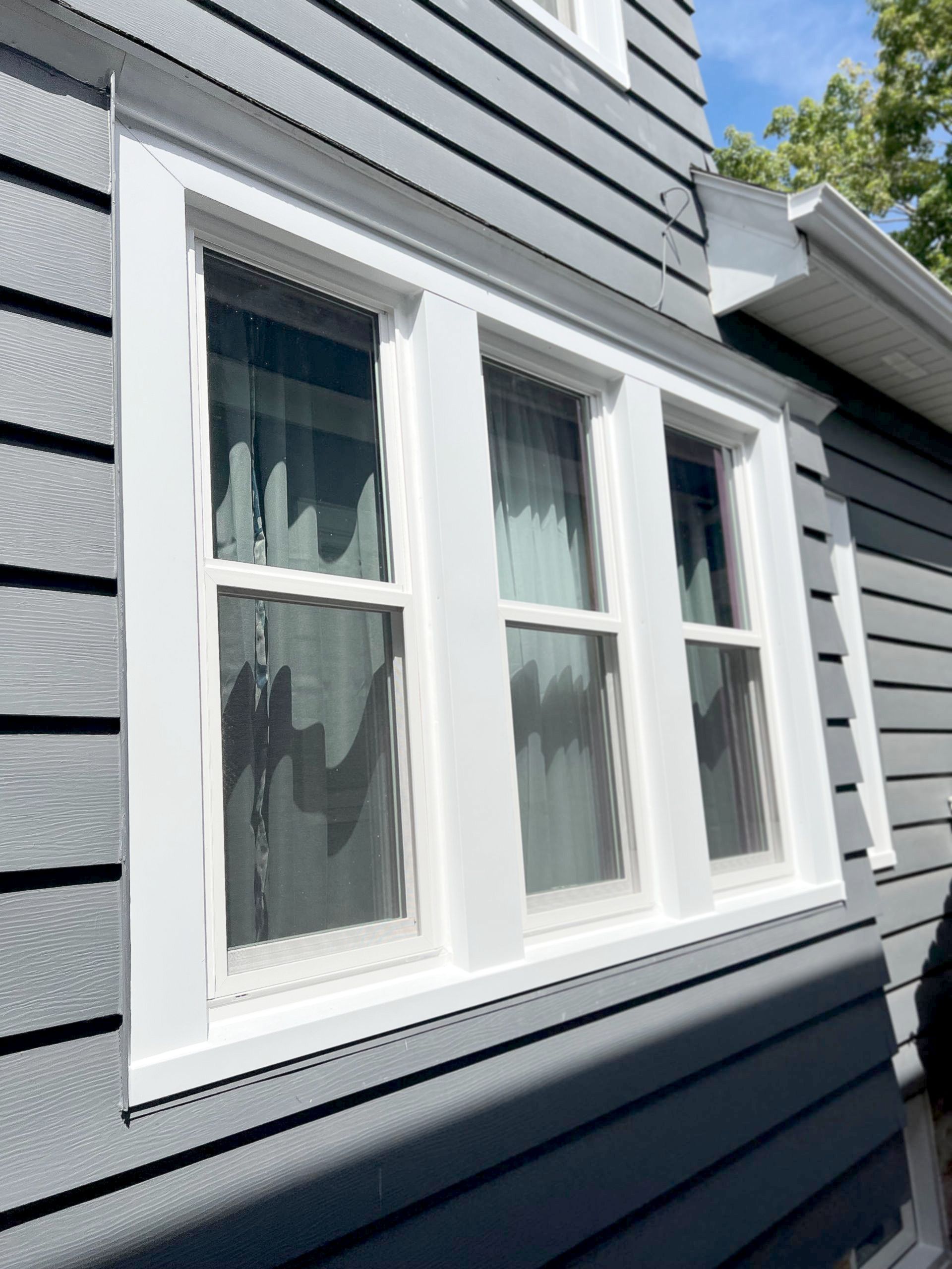White-framed windows on a gray-sided house.