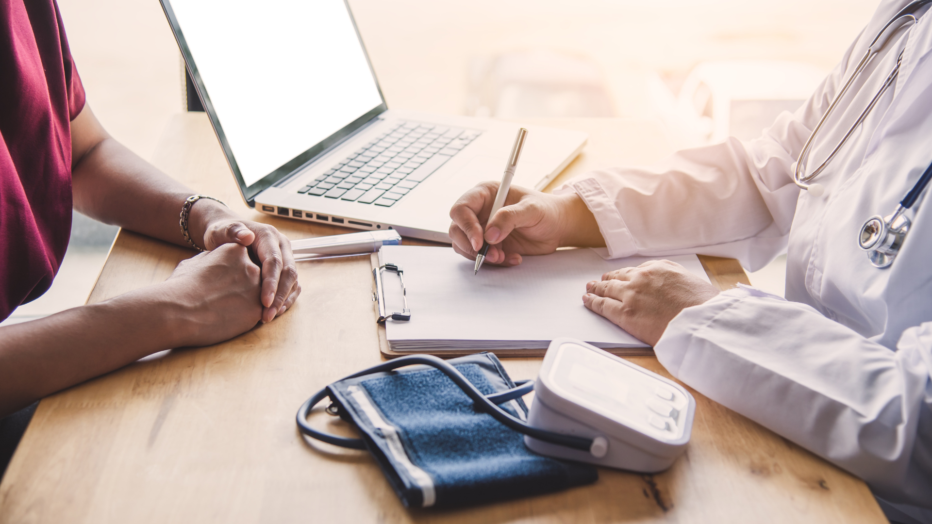 A doctor is writing on a clipboard while talking to a patient.