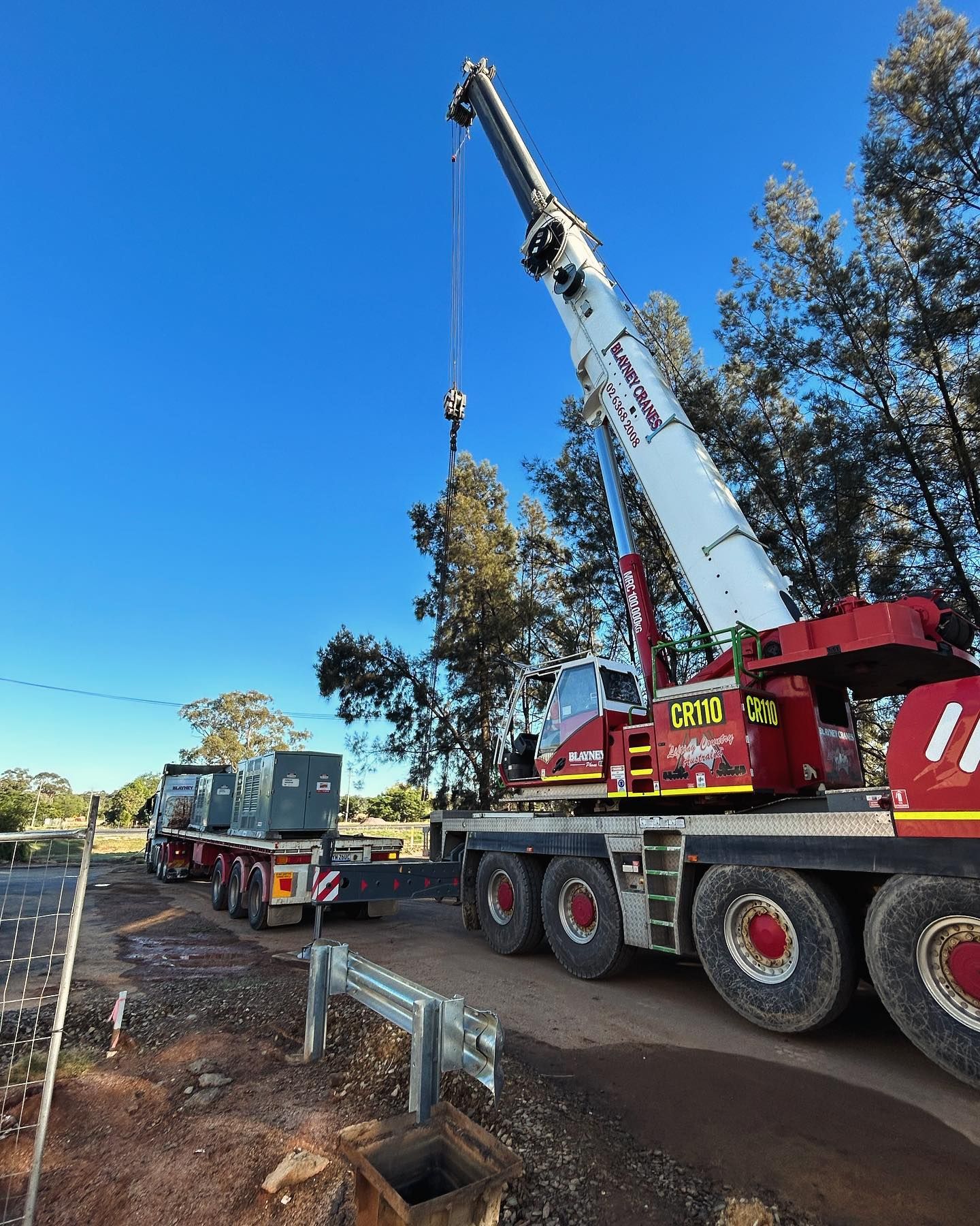 A Large Red and White Crane Lifting Equipment From a Trailer — Central West Power Construction in Orange, NSW