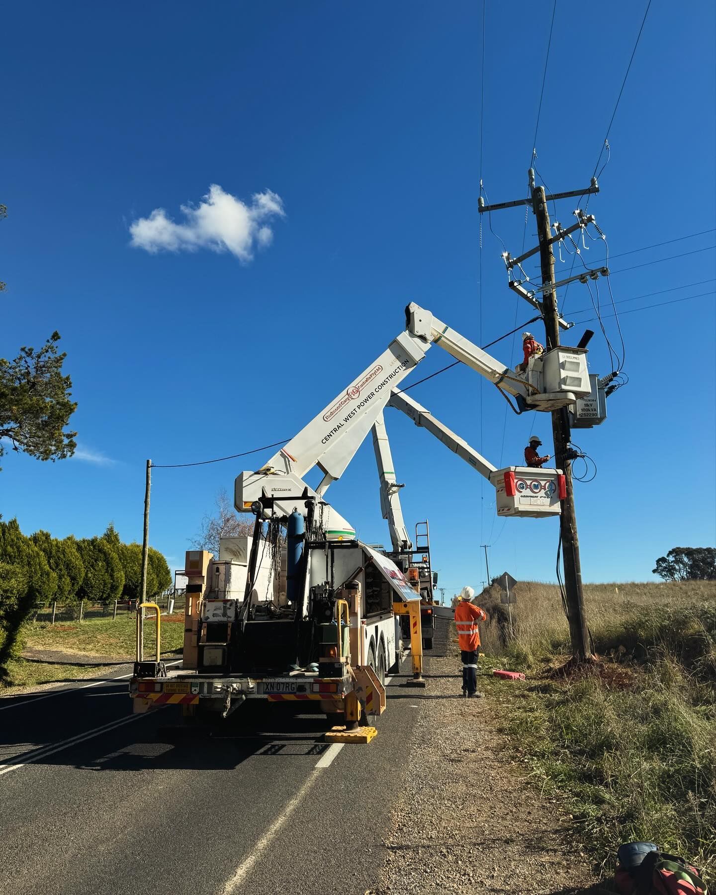 Linemen in Cherry Pickers Working on Power Lines Attached to a Utility Pole — Central West Power Construction in Orange, NSW